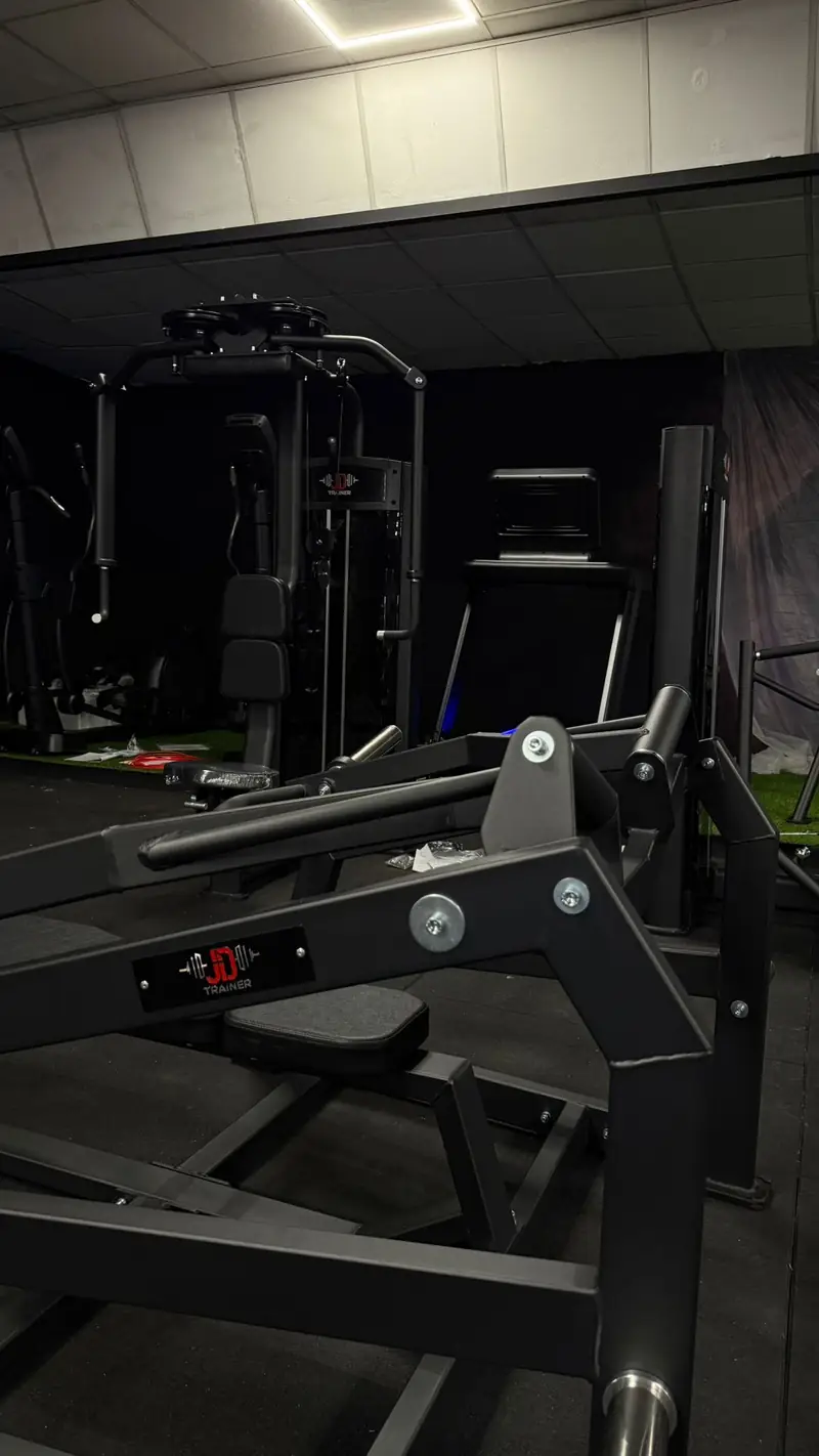 Máquina de piernas de carga con discos en la sala de JD Trainer