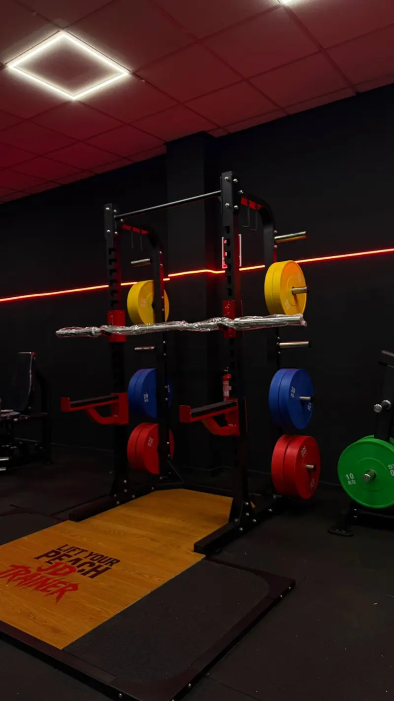 Rack de sentadillas con plataforma y discos de colores bajo la línea LED roja